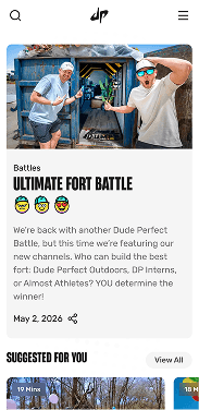 Dude Perfect mobile homepage featuring a member of the group relaxing on grass, with a headline promoting ad-free content and a link to explore the app.
